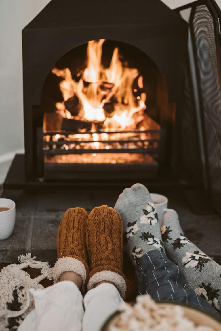 Person Wearing Gray and White Socks Near Brown Fireplace on one of the Cozy Winter Days